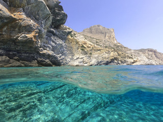 Above and below underwater photo of crystal clear sea paradise rocky seascape and small chapel of Agia Anna just next to iconic Hozoviotissa Monastery, Amorgos island, Cyclades, Greece