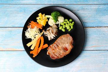 Pork Chop Steak served with mixed vegetable as stream carrot ,corn,green bean,lettuce and mushroom.