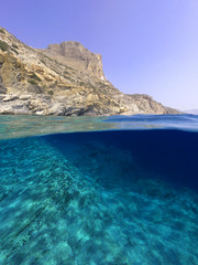 Above and below underwater photo of crystal clear sea paradise rocky seascape and small chapel of Agia Anna just next to iconic Hozoviotissa Monastery, Amorgos island, Cyclades, Greece