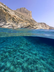 Above and below underwater photo of crystal clear sea paradise rocky seascape and small chapel of Agia Anna just next to iconic Hozoviotissa Monastery, Amorgos island, Cyclades, Greece