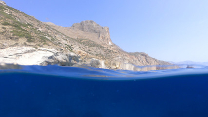 Above and below underwater photo of crystal clear sea paradise rocky seascape and small chapel of...