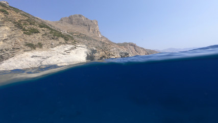 Above and below underwater photo of crystal clear sea paradise rocky seascape and small chapel of...
