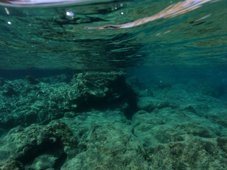 Beautiful underwater split above and below photo of rocky seascape with deep blue sky and clouds in tropical exotic island destination