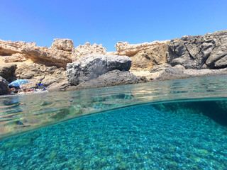 Above and below underwater photo of crystal clear turquoise beach of Kaminakia, Astypalaia island, Dodecanese, Greece