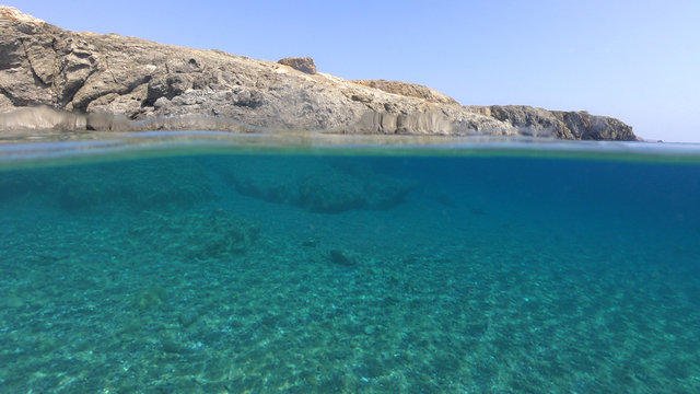 Beautiful underwater split above and below photo of rocky seascape with deep blue sky and clouds in tropical exotic island destination