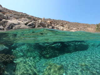 Above and below underwater photo of crystal clear turquoise beach of Kaminakia, Astypalaia island, Dodecanese, Greece