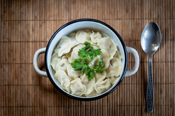Pelmeni, traditional Russian dumpling dish with meat on table - selective focus, top down photo 
