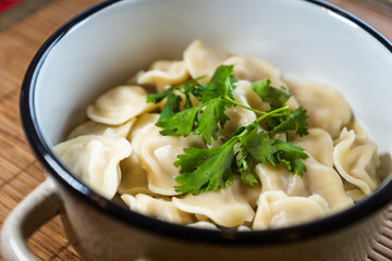 Pelmeni, traditional Russian dumpling dish with meat on table - selective focus, top down photo 