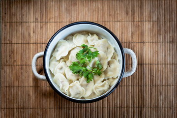 Pelmeni, traditional Russian dumpling dish with meat on table - selective focus, top down photo 
