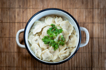 Pelmeni, traditional Russian dumpling dish with meat on table - selective focus, top down photo 