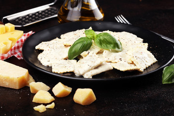 Ravioli with carbonara garnished with parmesan cheese and basil on rustic table