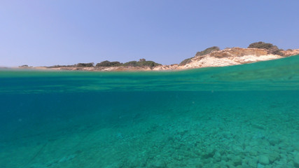 Above and below underwater photo of crystal clear sea paradise rocky seascape of Laki beach in Kato Koufonisi island, Cyclades, Greece