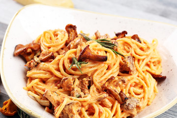 pasta with organic chanterelles. portion of spaghetti pasta with fried chanterelles in a creamy garlic sauce with cheese on a table
