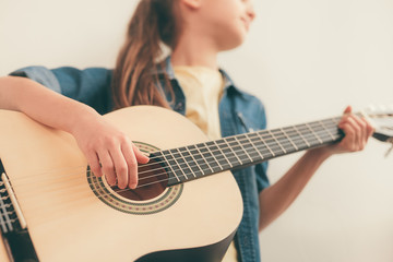Crop girl learning to play guitar