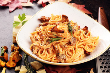 pasta with organic chanterelles. portion of spaghetti pasta with fried chanterelles in a creamy garlic sauce with cheese on a table