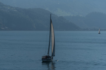 Fototapeta premium Yacht on a mountain lake in the background of mountains. Beautiful landscape