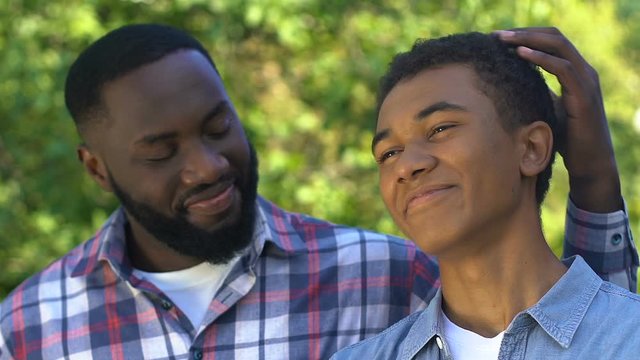 Happy black man hugging son and scratching his head, happy family, friendship