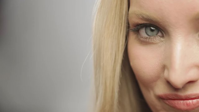 Half of caucasian blonde woman's face in studio smiling at camera
