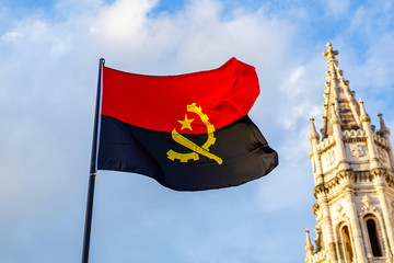 Angola flag waving in front of a blue sky.