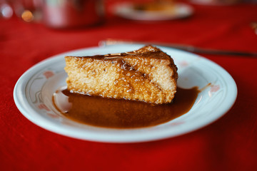 piece of flan served in a white plate on a red tablecloth, you can see the layers and melted caramel
