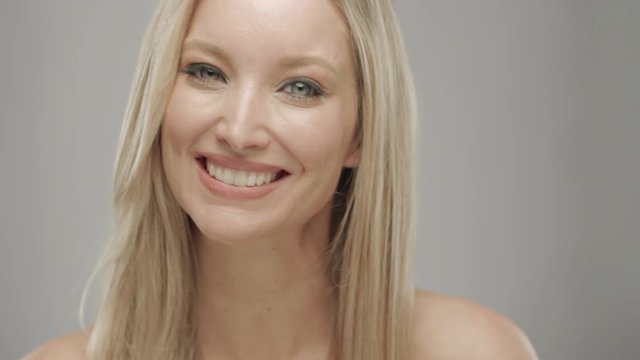 Caucasian blonde woman in studio smiling and laughing at camera
