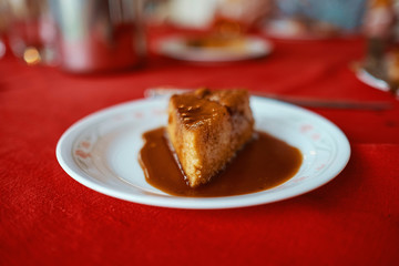 piece of flan served in a white plate on a red tablecloth, you can see the layers and melted caramel