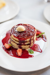Pancakes with berry sauce and fresh strawberries. Brunch in restaurant