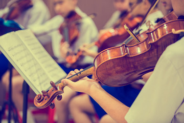 Asian boy students playing violin with music notation in the group. Violin player. Violinist hands...