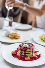 Brunch in restaurant. Pancakes with berry sauce and fresh strawberries.
