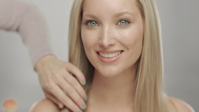 Makeup artist applying blush to cheek of woman