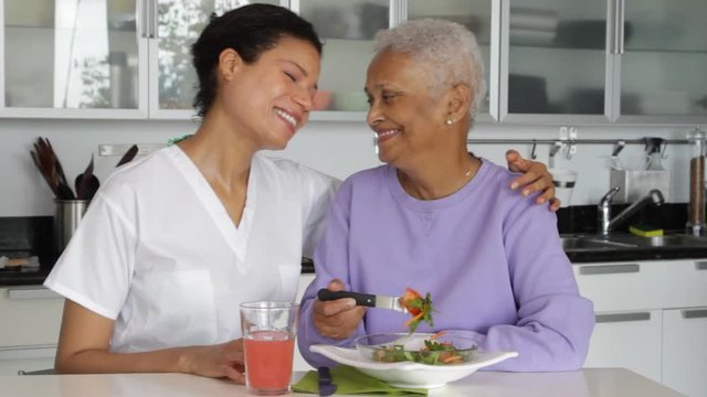 Senior woman with caregiver eating salad