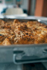 meat lasagna on a metal tray, gratin ready to eat on the table