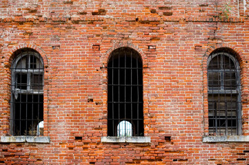 brick wall of an old abandoned prison with bars on the windows