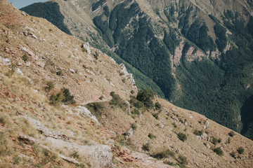 A vertical shot of mountains and hills with a lot of rocks under the beautiful blue sky