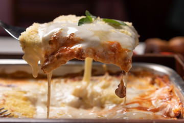 Delicious lasagna made with minced beef bolognese sauce and bechamel sauce topped with basil leaves, soft light