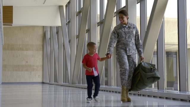 African American soldier and son walking in airport