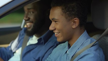 Smiling african-american teacher comforting teenage student, driving school