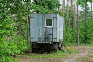 Fototapeta na wymiar one old gray metal trailer stands in green vegetation in nature