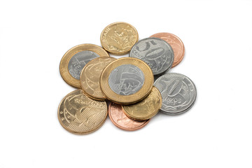 A close up pile of a shiny assortment of Brazilian coins isolated, in macro, on a clean, white background
