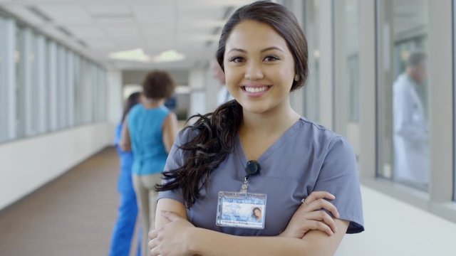 Serious nurse posing in hospital corridor then smiling