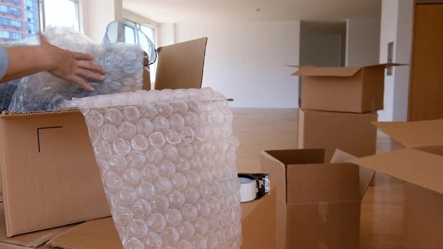 Hands of Asian woman wrapping vase with bubble wrap