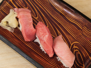 Set of three tuna sushi on a wooden plate