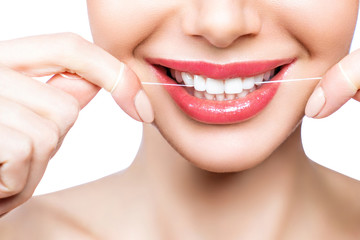 Young beautiful woman is engaged in cleaning teeth. Beautiful smile healthy white teeth. A girl holds a dental floss. The concept of oral hygiene.