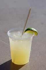 A refreshing margarita cocktail on the rocks with a slice of lime served at the beach on a warm summer day