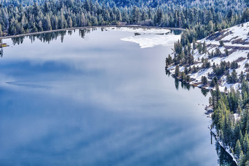 Calm clear and cold higher elevation. mountain lake surrounded by pristine forest of pine trees in Yosemite
