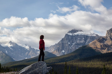 Girl enjoying the beautiful scenery of the Canadian Rockies during a cloudy and sunny summer day. Taken on Icefields Parkway, Banff, Alberta, Canada.