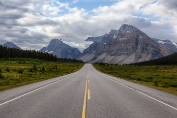 Scenic road in the Canadian Rockies during a vibrant sunny and cloudy summer morning. Taken in Icefields Parkway, Banff National Park, Alberta, Canada.