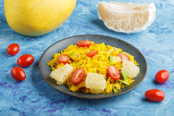 Fried pomelo with tomatoes and avocado on blue concrete background. side view.