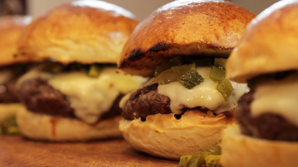 A bunch of hamburgers in brioche buns and cheese close up