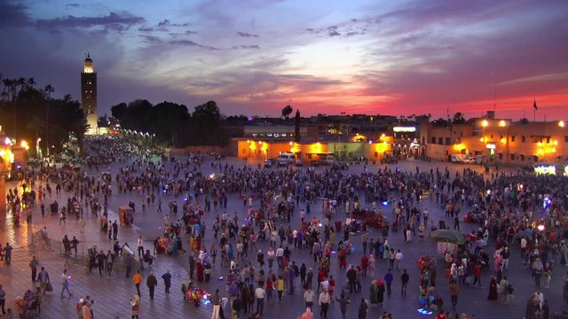 Zoom out of people walking outdoors at night, Marrakesh, Morocco